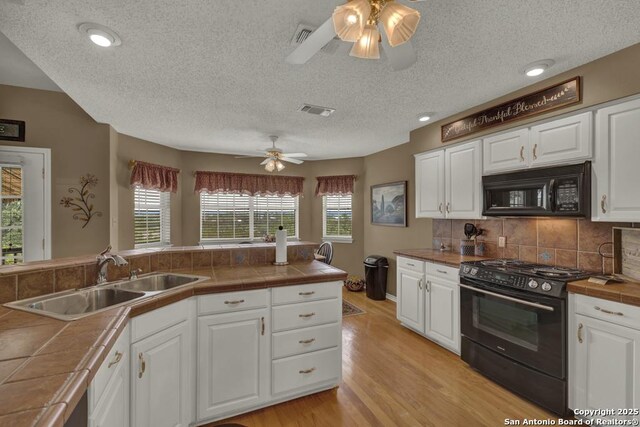 821 Lakeview, Canyon Lake, TX 78133 - kitchen with black appliances, a sink, ceiling fan, tile counters, and a textured ceiling