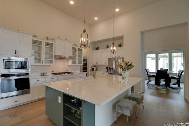 128 Maravillas, Boerne, TX 78006 - kitchen with appliances with stainless steel finishes, high vaulted ceiling, tasteful backsplash, an island with sink, and white cabinets