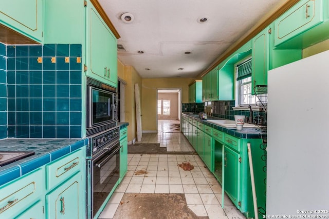 3311 W Commerce St, San Antonio, TX 78228 - kitchen featuring tile counters, green cabinets, black appliances, and light tile patterned flooring