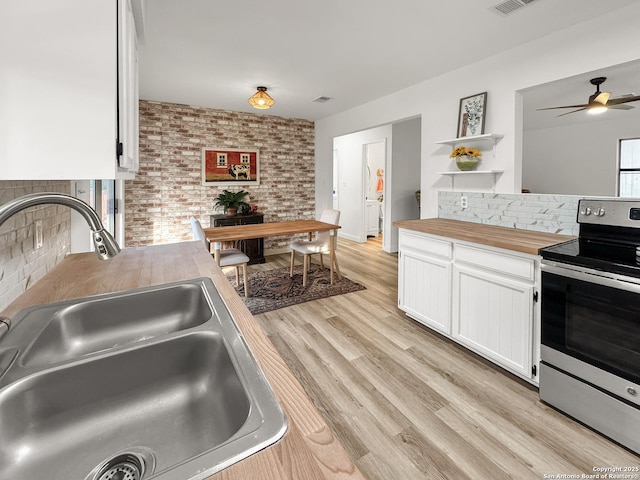 1412 Laurie, Canyon Lake, TX 78133 - kitchen with stainless steel electric range oven, a sink, open shelves, butcher block countertops, and white cabinetry
