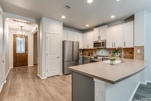 10442 Macarthur, Converse, TX 78109 - kitchen with appliances with stainless steel finishes, arched walkways, a sink, light wood-type flooring, and recessed lighting