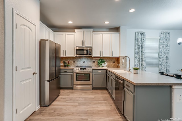10442 Macarthur, Converse, TX 78109 - kitchen with appliances with stainless steel finishes, gray cabinetry, a sink, a peninsula, and light wood-style flooring