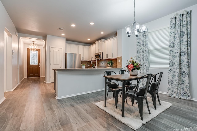 10442 Macarthur, Converse, TX 78109 - dining space featuring a chandelier, arched walkways, light wood finished floors, and recessed lighting