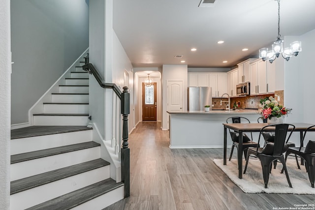 10442 Macarthur, Converse, TX 78109 - dining room with a chandelier, light wood-style floors, stairs, arched walkways, and recessed lighting