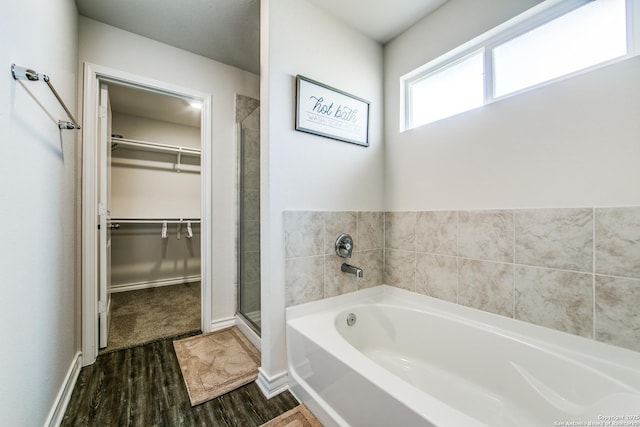 7610 Eclipse Mark, San Antonio, TX 78252 - bathroom featuring a bath, wood finished floors, a walk in closet, a stall shower, and baseboards