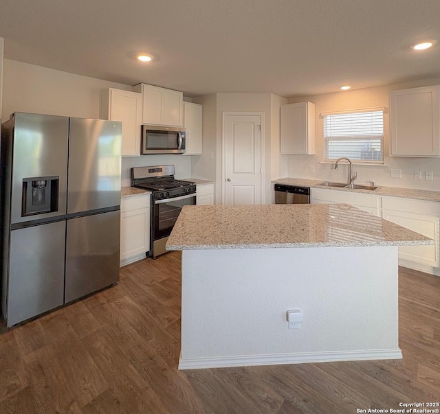 15302 Smoky Honeyeater, San Antonio, TX 78253 - kitchen featuring appliances with stainless steel finishes, a center island, white cabinetry, light stone counters, and dark wood-style flooring