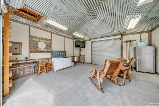 104 Bayberry Ct, La Vernia, TX 78121 - garage with freestanding refrigerator, a workshop area, and electric panel
