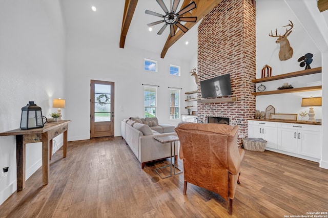 104 Bayberry Ct, La Vernia, TX 78121 - living room with a towering ceiling, light wood finished floors, a fireplace, beam ceiling, and baseboards