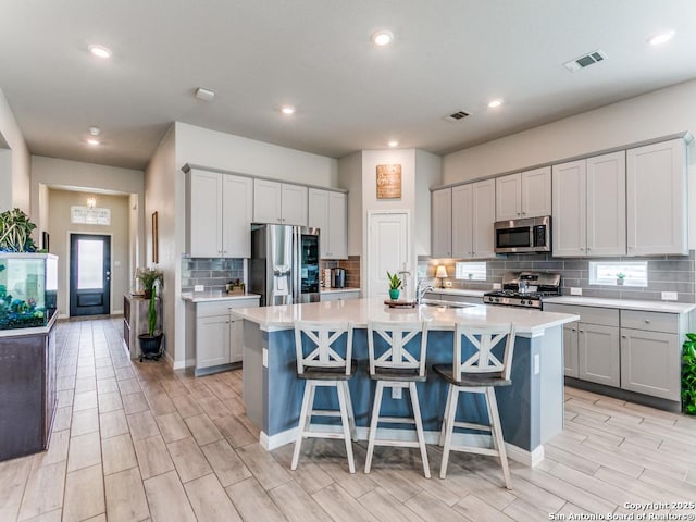 5344 Jasmine, Bulverde, TX 78163 - kitchen featuring appliances with stainless steel finishes, light countertops, backsplash, a kitchen island with sink, and wood finish floors