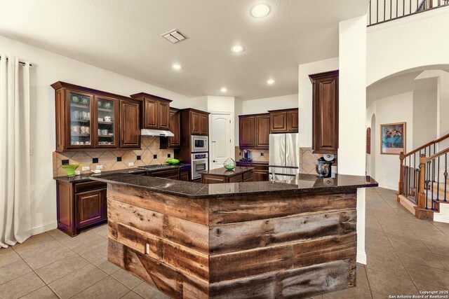 25702 Willard Path, San Antonio, TX 78261 - kitchen featuring arched walkways, appliances with stainless steel finishes, under cabinet range hood, light tile patterned floors, and recessed lighting