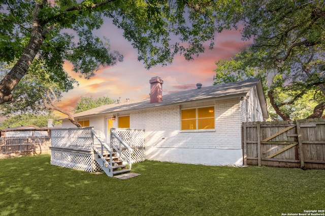 2723 Woodline, San Antonio, TX 78251 - back of house at dusk with brick siding, a wooden deck, a chimney, and a gate