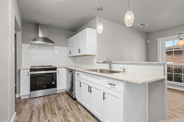 2723 Woodline, San Antonio, TX 78251 - kitchen with appliances with stainless steel finishes, wall chimney range hood, a sink, light wood-type flooring, and white cabinets