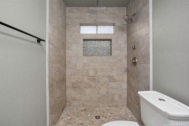 2723 Woodline, San Antonio, TX 78251 - bathroom featuring tiled shower, a textured wall, and toilet