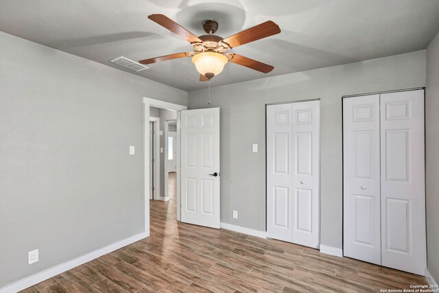 2723 Woodline, San Antonio, TX 78251 - unfurnished bedroom with two closets, wood finished floors, baseboards, and a ceiling fan