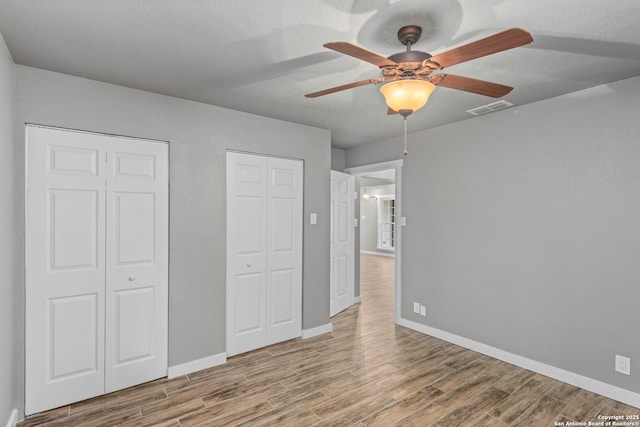 2723 Woodline, San Antonio, TX 78251 - unfurnished bedroom with wood finished floors, baseboards, and multiple closets
