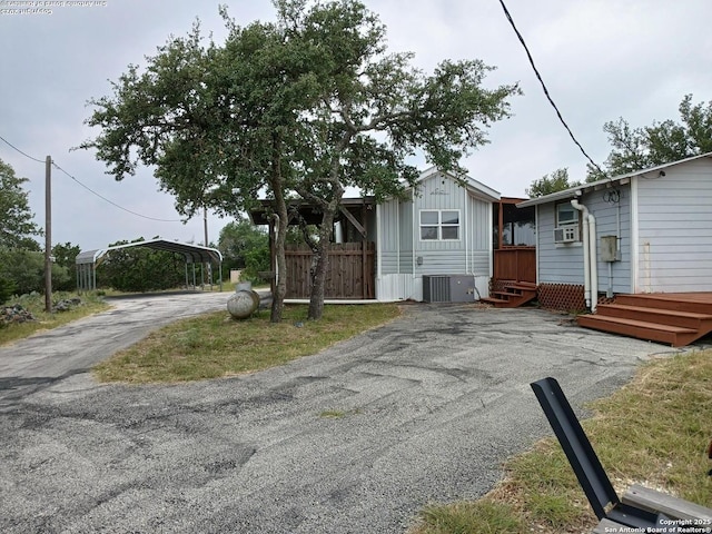 2362 Timbercreek, Pipe Creek, TX 78063 - view of front of property with a carport, asphalt driveway, central AC unit, board and batten siding, and cooling unit