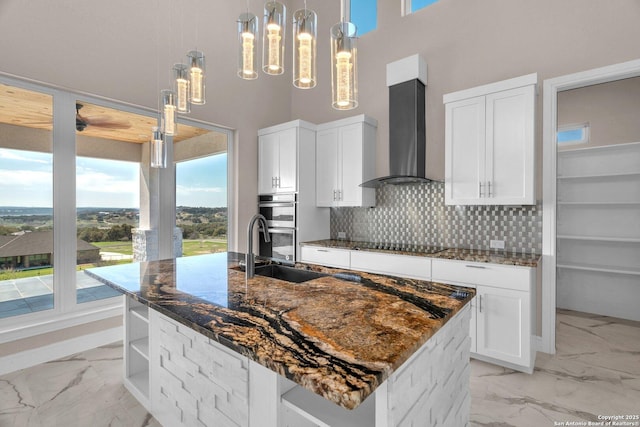 142 Wizard, Spring Branch, TX 78070 - kitchen featuring wall chimney exhaust hood, a sink, light marble finish flooring, a center island with sink, and a high ceiling