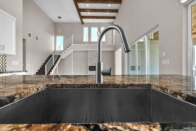 142 Wizard, Spring Branch, TX 78070 - kitchen view of beam ceiling, dark stone counters, a sink, and white cabinets
