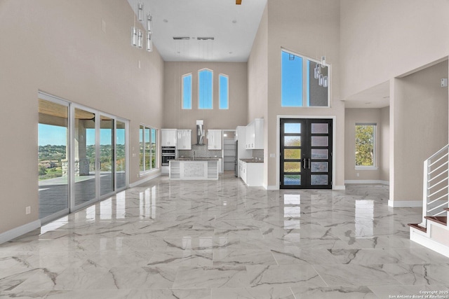 142 Wizard, Spring Branch, TX 78070 - unfurnished living room with light marble finish flooring, a high ceiling, baseboards, and french doors