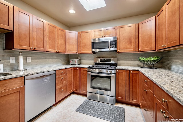 3811 E Songbird Ln, San Antonio, TX 78229 - kitchen featuring stainless steel appliances, a skylight, tasteful backsplash, light stone counters, and recessed lighting