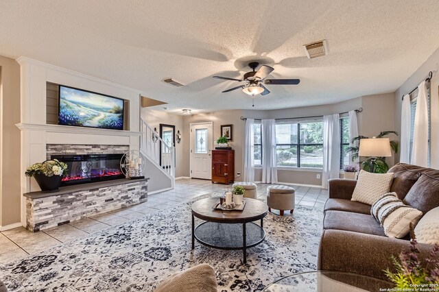 2334 Creekside Bnd, San Antonio, TX 78259 - living room featuring a textured ceiling, baseboards, a ceiling fan, tile patterned flooring, and a stone fireplace