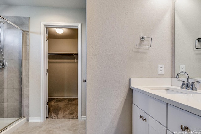 5614 Burr Blf, San Antonio, TX 78266 - full bathroom with vanity, a spacious closet, a shower stall, tile patterned flooring, and a textured wall
