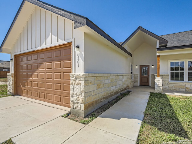 8501 Utopia Blvd, Selma, TX 78154 - view of front facade with board and batten siding, stone siding, an attached garage, concrete driveway, and a shingled roof