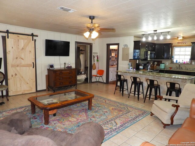 155 Scenic Cir, Lakehills, TX 78063 - living area featuring light tile patterned flooring, a barn door, and ceiling fan