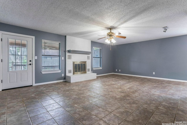 210 Cardinal, New Braunfels, TX 78130 - unfurnished living room featuring ceiling fan, baseboards, a textured ceiling, and a brick fireplace