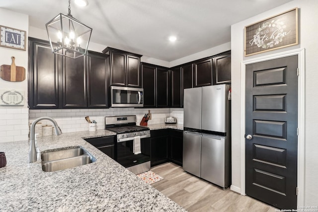 4902 Oxbow Bnd, Saint Hedwig, TX 78152 - kitchen featuring appliances with stainless steel finishes, a sink, a chandelier, light stone counters, and backsplash