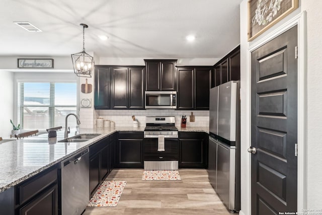 4902 Oxbow Bnd, Saint Hedwig, TX 78152 - kitchen with stainless steel appliances, a sink, light wood-style floors, tasteful backsplash, and light stone counters
