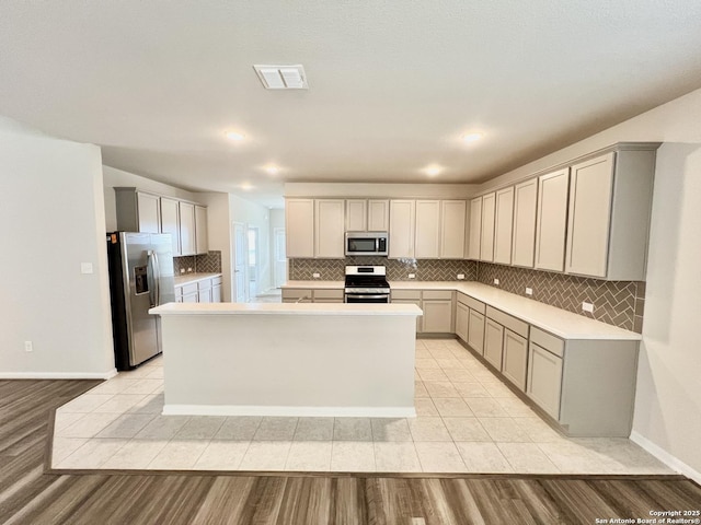 4823 Cambridge Park, Converse, TX 78109 - kitchen featuring stainless steel appliances, backsplash, gray cabinets, and a center island