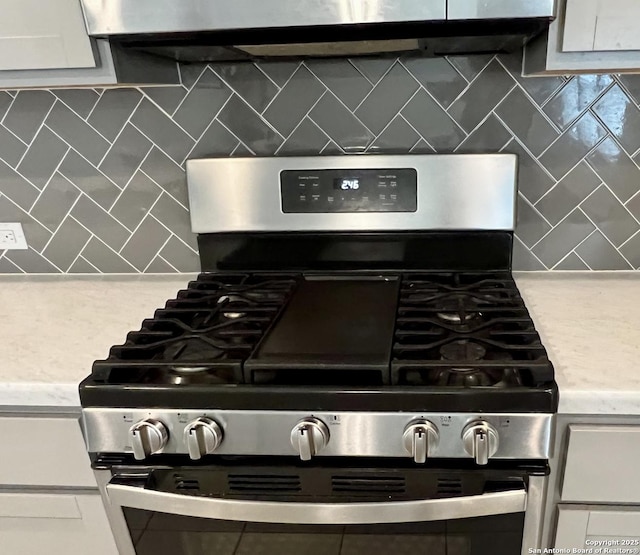 4823 Cambridge Park, Converse, TX 78109 - kitchen view of stainless steel gas range, backsplash, light countertops, under cabinet range hood, and white cabinets