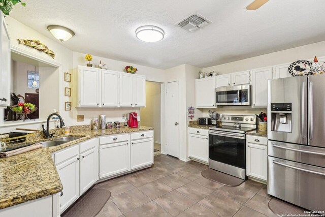 14026 Fairway Oaks, San Antonio, TX 78217 - kitchen with stainless steel appliances, a sink, white cabinets, dark tile patterned floors, and light stone countertops
