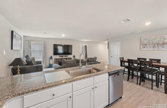 734 Ambush Rdg, San Antonio, TX 78219 - kitchen with stainless steel dishwasher, a sink, white cabinetry, light wood finished floors, and open floor plan