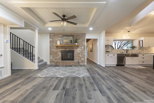 3160 Weil, Marion, TX 78124 - unfurnished living room featuring a raised ceiling, dark wood-type flooring, a sink, a ceiling fan, and a brick fireplace