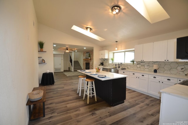 3160 Weil, Marion, TX 78124 - kitchen featuring a skylight, wood finished floors, tasteful backsplash, white cabinetry, and vaulted ceiling
