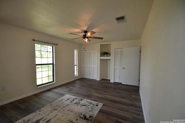 3160 Weil, Marion, TX 78124 - unfurnished bedroom featuring multiple closets, dark wood-style floors, baseboards, and ceiling fan