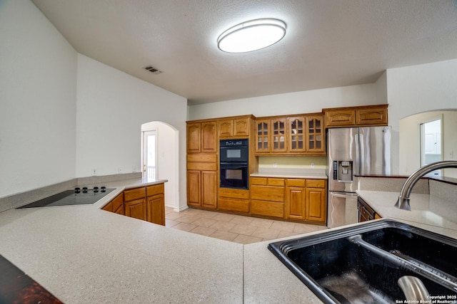 3343 Dove Park Ln, San Antonio, TX 78253 - kitchen with arched walkways, black appliances, brown cabinets, and a textured ceiling