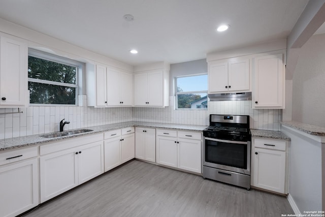 1129 N Smith St, San Antonio, TX 78207 - kitchen with gas range, a sink, under cabinet range hood, backsplash, and light wood-style floors