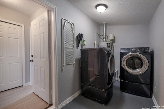 1129 N Smith St, San Antonio, TX 78207 - laundry room featuring separate washer and dryer, a textured ceiling, light wood-type flooring, water heater, and baseboards