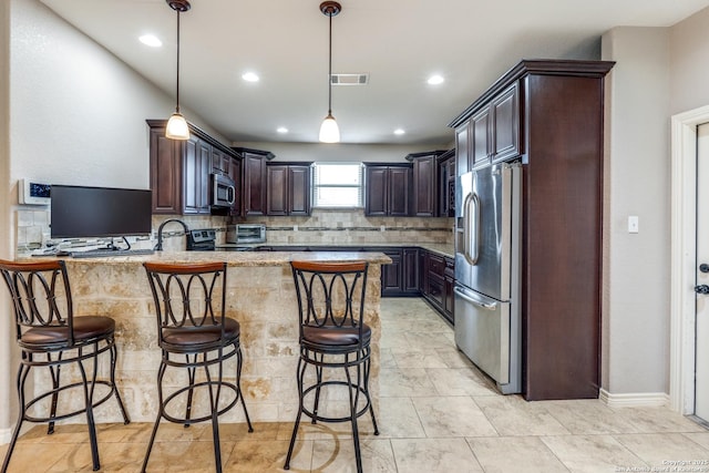 712 Crestview, Floresville, TX 78114 - kitchen featuring appliances with stainless steel finishes, a peninsula, dark brown cabinets, a breakfast bar, and recessed lighting