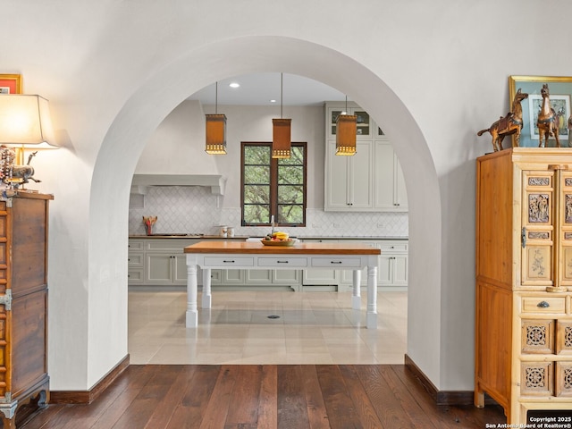 2835 Palomino Spgs, Bandera, TX 78003 - kitchen with wood counters, dark wood-type flooring, arched walkways, and backsplash