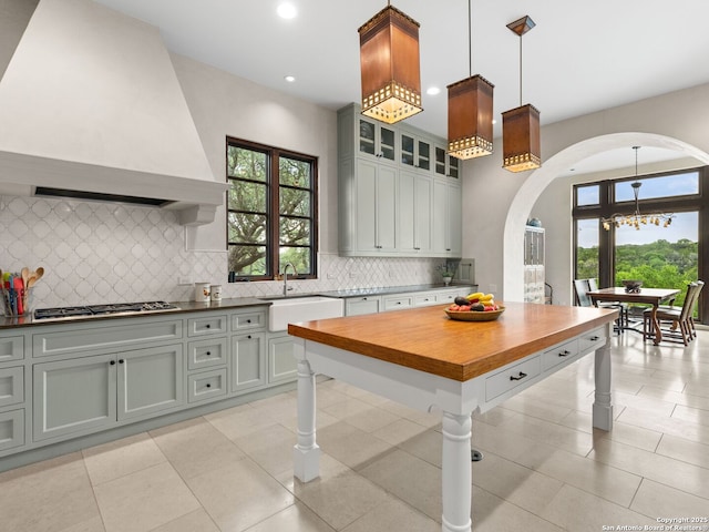 2835 Palomino Spgs, Bandera, TX 78003 - kitchen with arched walkways, a sink, premium range hood, stainless steel gas cooktop, and decorative backsplash