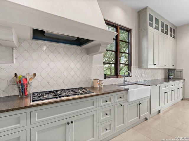 2835 Palomino Spgs, Bandera, TX 78003 - kitchen with a sink, stainless steel gas cooktop, backsplash, light tile patterned floors, and glass insert cabinets