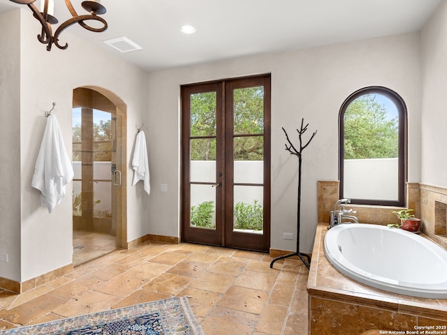 2835 Palomino Spgs, Bandera, TX 78003 - bathroom featuring french doors, stone tile floors, a bath, a stall shower, and recessed lighting