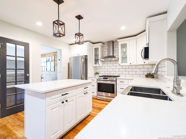 221 Harmon, San Antonio, TX 78209 - kitchen with wall chimney range hood, appliances with stainless steel finishes, a sink, light wood-type flooring, and tasteful backsplash