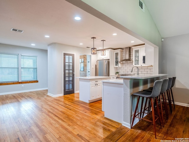 221 Harmon, San Antonio, TX 78209 - kitchen featuring wall chimney range hood, freestanding refrigerator, a peninsula, a kitchen island, and light wood-style floors