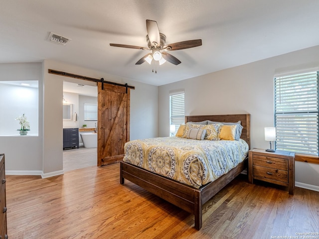 221 Harmon, San Antonio, TX 78209 - bedroom with a barn door, light wood-type flooring, baseboards, connected bathroom, and ceiling fan