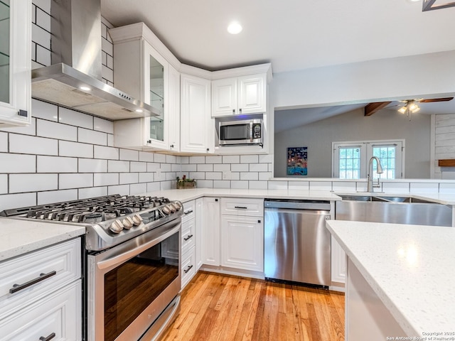 221 Harmon, San Antonio, TX 78209 - kitchen with appliances with stainless steel finishes, wall chimney range hood, a sink, a ceiling fan, and tasteful backsplash